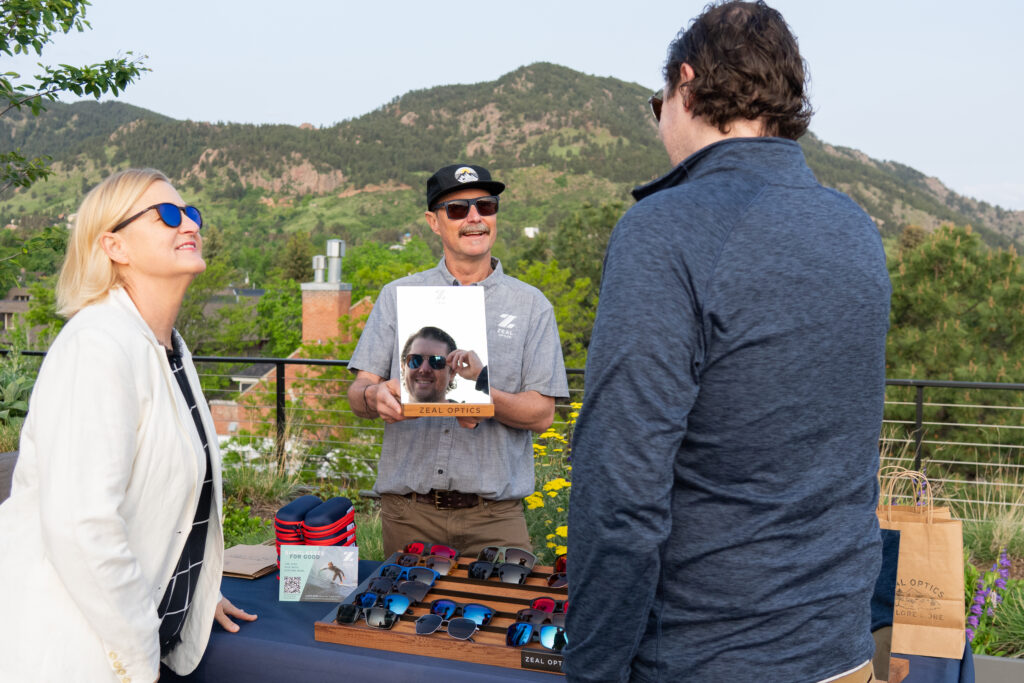 man holding bag in front of table of Zeal sunglasses