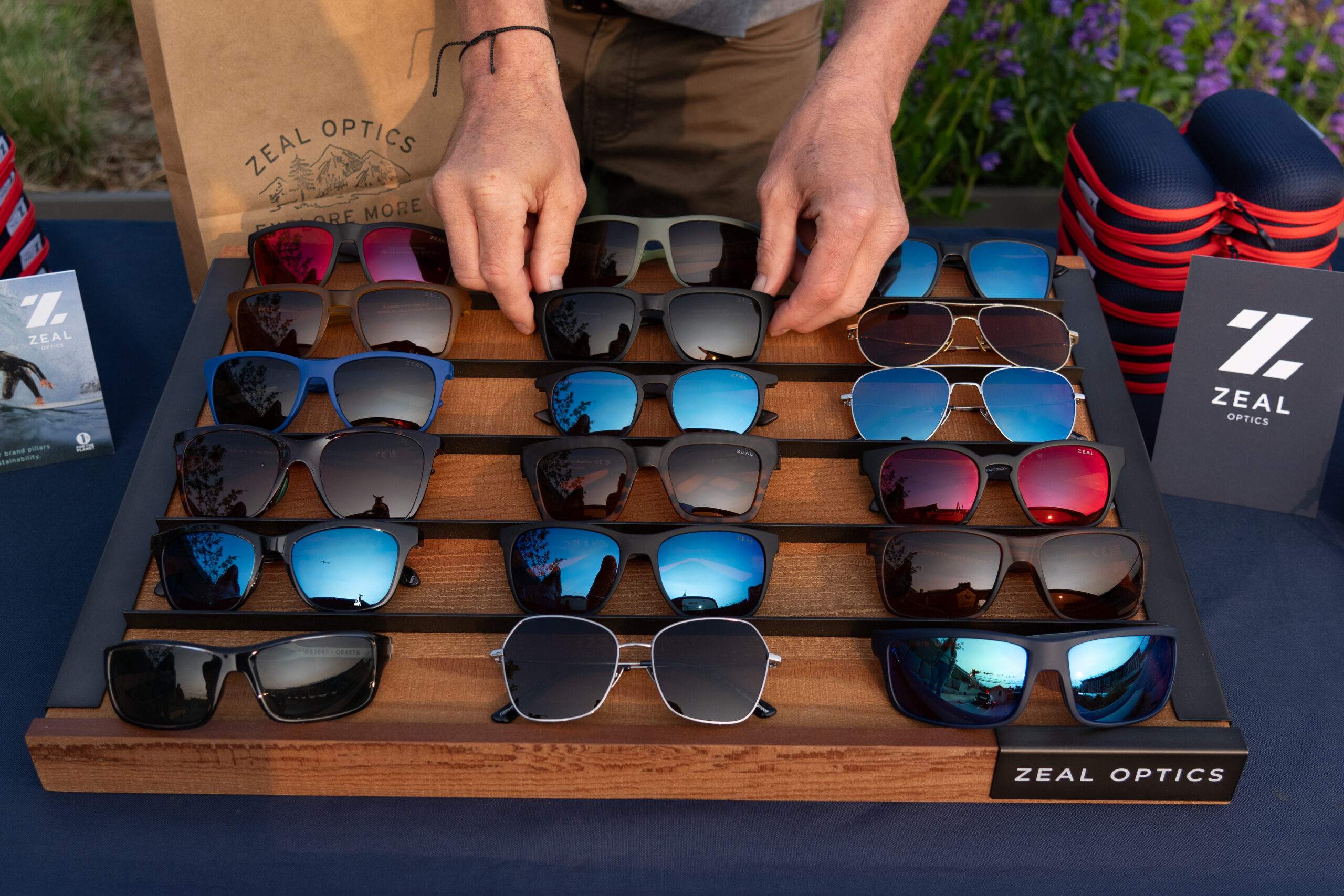 man holding bag in front of table of Zeal sunglasses
